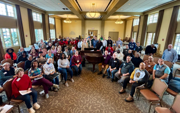 Group photo of the Georgia Symphony Orchestra Chorus seated around a piano